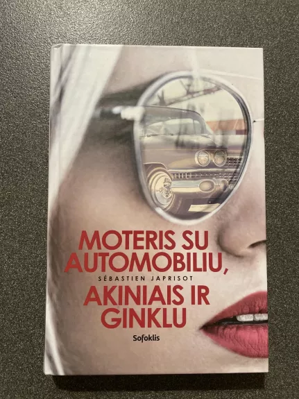 Moteris su automobiliu, akiniais ir ginklu