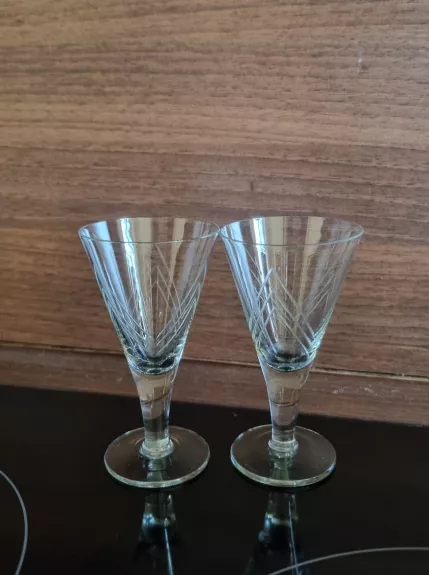 Dvi trikampės taurelės ant kojelės.